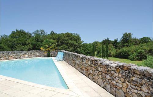 a swimming pool with a stone wall and a chair at Awesome Home In Padirac With Kitchenette in Padirac