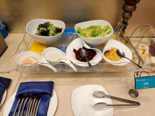 a tray with bowls of vegetables and spoons on a table at Skytel Hotel Chengdu-City Center in Chengdu