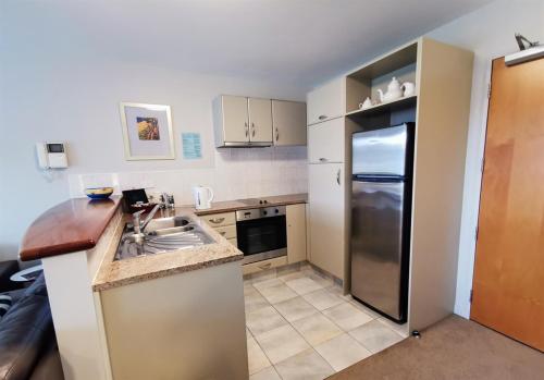 a kitchen with a sink and a refrigerator at The Anchorage Apartments in Mount Maunganui