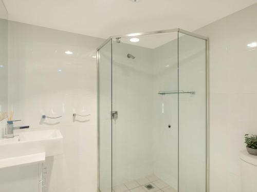 a bathroom with a glass shower and a sink at Wharf Apartment Unit 11 in Narooma