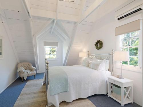 una camera da letto bianca con un letto e una sedia di The Cottage a Kianga