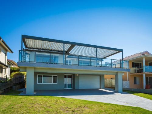 
a large white building with a blue roof at 81 Dalmeny Drive - Beach House in Kianga
