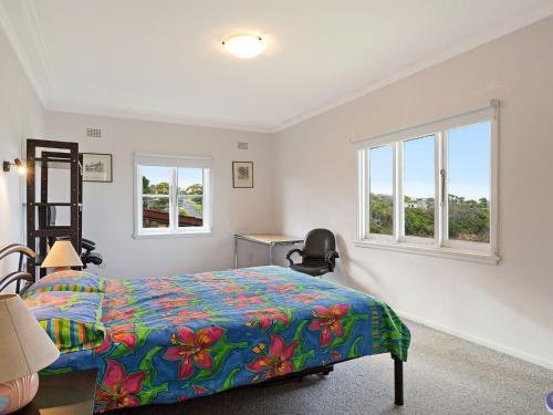 a bedroom with a bed and two windows at 84 Ocean Parade in Dalmeny