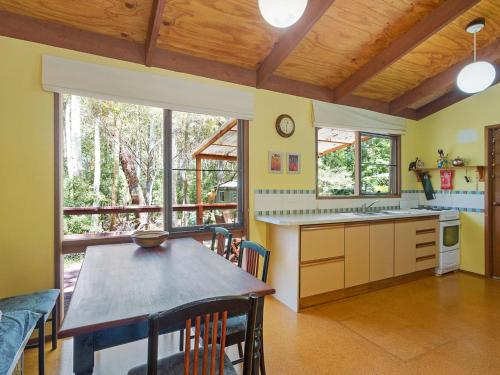 a kitchen with a table and some chairs in a room at Caseys Pet Friendly Beach Cottage in Mystery Bay