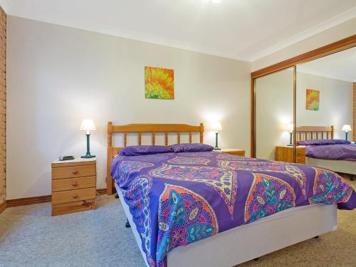 1 dormitorio con 1 cama extragrande y espejo en Grand Pacific 2 Unit 1 - Ground Floor en Narooma