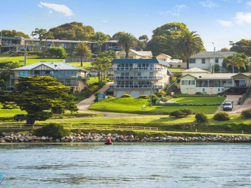 a person in a boat on the water in front of houses at Sapphire Waters Unit 3 in Narooma