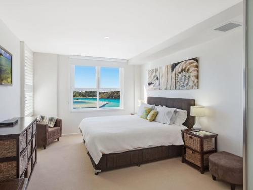 - une chambre avec un grand lit et une fenêtre dans l'établissement Wharf Apartment Unit 7, à Narooma