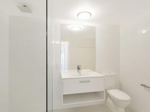 a white bathroom with a toilet and a sink at Luxury Beach House in Kianga