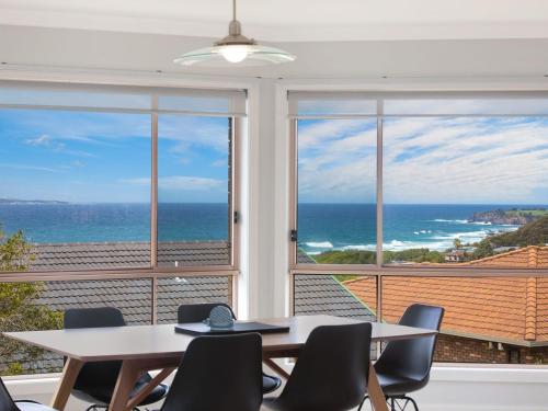 a dining room with two tables and a view of the ocean at 4 Dawn Parade Kianga in Kianga