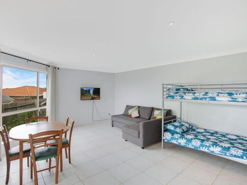 a living room with a couch a table and a bed at 4 Dawn Parade Kianga in Kianga