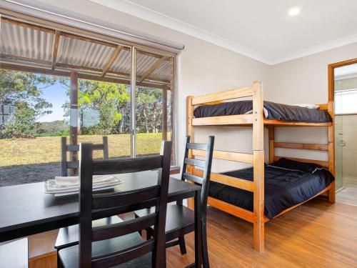 a dining room with a dining table and bunk beds at Braeside Cabin Four Ziera in Central Tilba