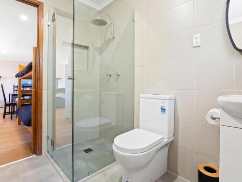 a bathroom with a toilet and a glass shower at Braeside Cabin Four Ziera in Central Tilba