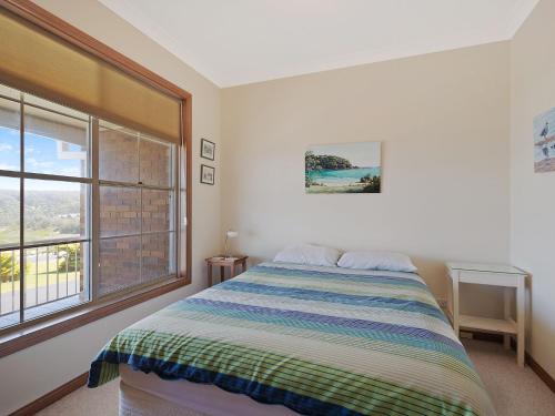 a bedroom with a bed and a large window at 120 Ocean Parade Dalmeny in Dalmeny