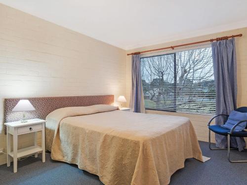 een slaapkamer met een bed en een groot raam bij Apollo Unit 23 First Floor in Narooma