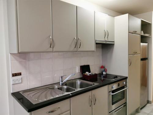 a kitchen with white cabinets and a sink at The Anchorage Apartments in Mount Maunganui