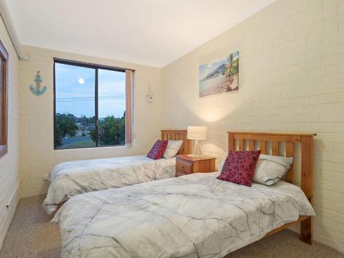 two beds in a room with a window at Apollo Unit 8 1st Floor in Narooma