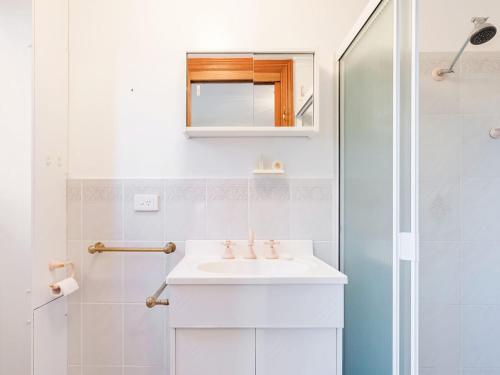 ナルーマにあるGrand Pacific 2 Unit 2 - Ground Floorの洗面台とシャワー付きの白いバスルーム