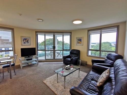 a living room with a leather couch and a television at The Anchorage Apartments in Mount Maunganui