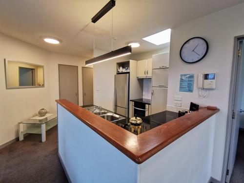 a kitchen with a counter with a clock on the wall at The Anchorage Apartments in Mount Maunganui