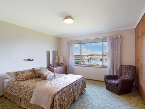 a bedroom with a bed and a window and a chair at 2 Water Crescent Retro Haven in Kianga