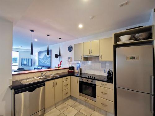 a kitchen with yellow cabinets and a white refrigerator at The Anchorage Apartments in Mount Maunganui