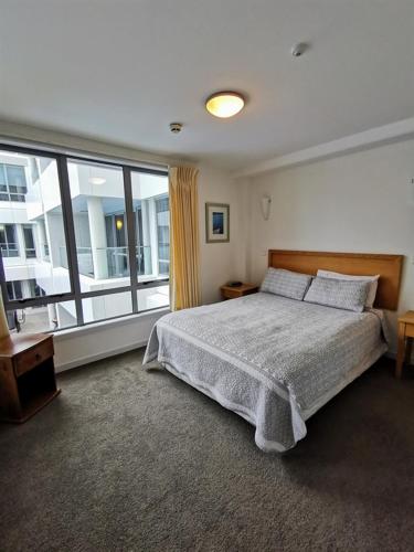 a bedroom with a bed and a large window at The Anchorage Apartments in Mount Maunganui