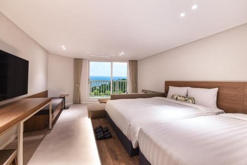 西歸浦的住宿－Kensington Resort Jeju Jungmun，酒店客房设有两张床和一台平面电视。