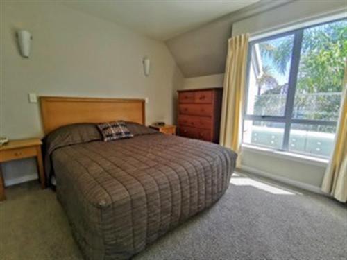 a bedroom with a bed and a large window at The Anchorage Apartments in Mount Maunganui