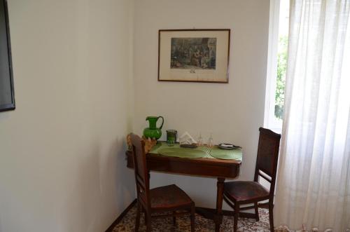 a dining room table with two chairs and a green vase on it at Green Quercia Apartment in Como