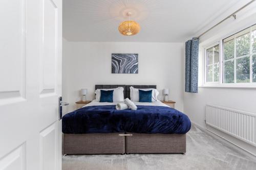 a bedroom with a bed with a blue comforter at Maunsell House - Lovely central home near Designer Outlets & town with parking in Ashford