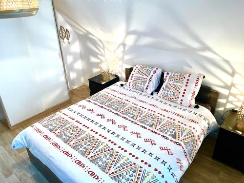 a bedroom with a bed with red and white blankets and pillows at Bel appartement « The Lion King » proche Disney in Montévrain