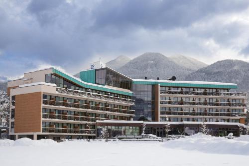 a large building in the snow in front of mountains at Bohinj Eco Hotel in Bohinj
