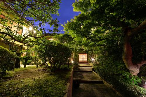 a wooden pathway leading to a building with a tree at Ryotei Jyusouya in Sango