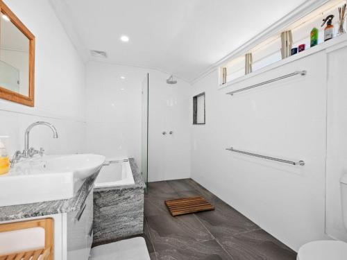 a white bathroom with a sink and a shower at Salty Sea Cottage in Narooma