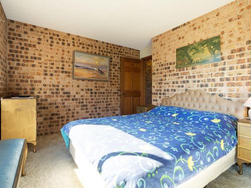 a bedroom with a bed and a brick wall at Pacific Pines Unit 4 in Narooma