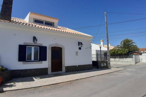 a white house with a door on a street at A Casa da Foz Moradia com vista mar in Sesimbra