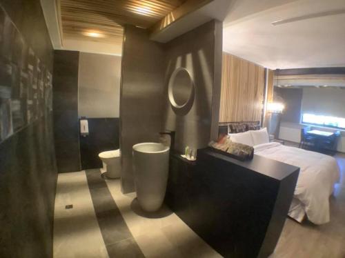 a bedroom with a bed and a bathroom with a tub at OUGE Motel Kaohsiung in Kaohsiung