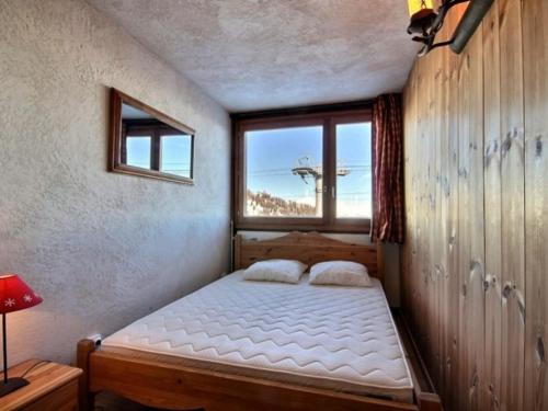 a bed in a room with a large window at Appartement La Plagne, 3 pièces, 6 personnes - FR-1-455-57 in La Plagne