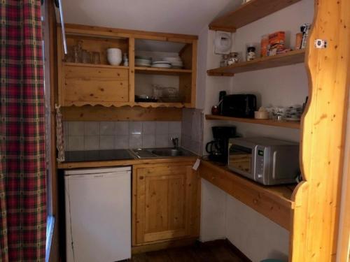 uma pequena cozinha com armários de madeira e um micro-ondas em Studio Brides-les-Bains, 1 pièce, 4 personnes - FR-1-512-171 em Brides-les-Bains