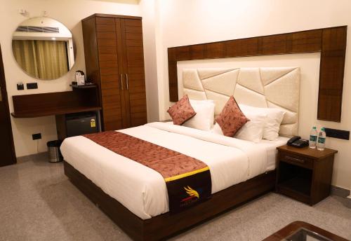 a bedroom with a large bed and a mirror at Hotel Doon's Pride in Dehradun