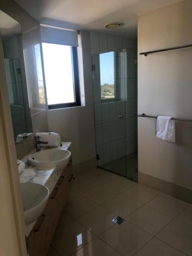 a bathroom with two sinks and a glass shower at Grand Mercure Allegra Hervey Bay in Hervey Bay