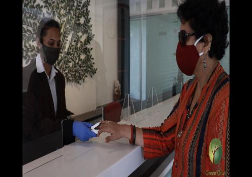 a woman wearing a face mask in front of a counter at Hotel Green Olive in Aurangabad