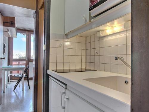 a white kitchen with a sink and a table at Studio La Plagne, 1 pièce, 2 personnes - FR-1-455-161 in La Plagne