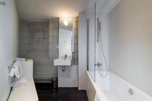 a bathroom with a tub and a sink and a shower at SOZO Hotel in Nantes