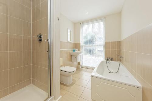 La salle de bains est pourvue d'une baignoire, de toilettes et d'une douche. dans l'établissement Flagstaff Apartment with Secure Parking, à Kent