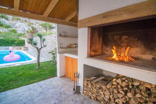 a fireplace in a house with a swimming pool at Village holiday apartman with heated pool Maslina in Kostanje