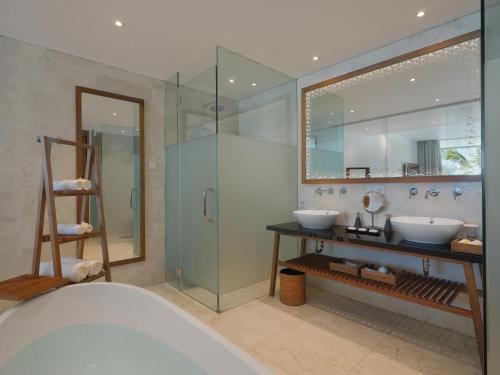 a bathroom with two sinks and a glass shower at Candi Beach Resort & Spa in Candidasa