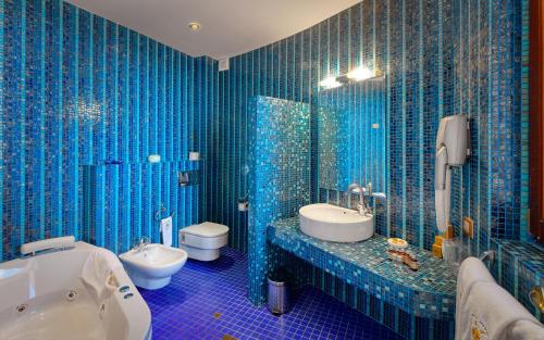 a blue tiled bathroom with a toilet and a sink at Hotel Soli Invicto in Elenovo