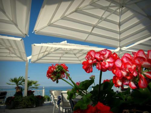 a table with white umbrellas and red flowers at Hotel Neva in Podstrana