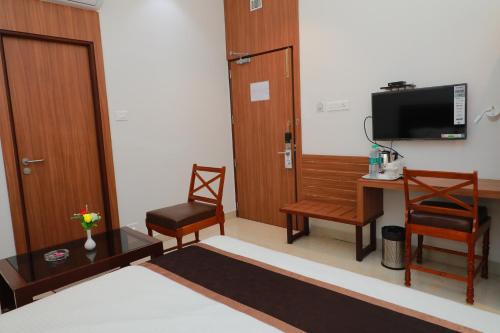 a room with a bed and a desk and a television at TM INN Hotel in Kanchipuram